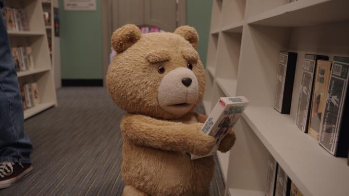 Ted picks up a VHS tape off a library shelf, looking surprised