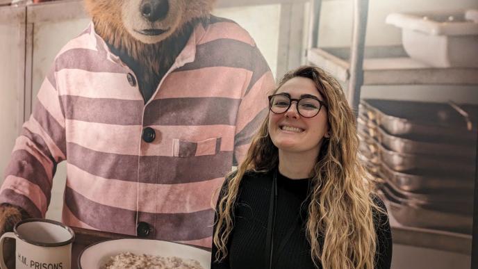 A woman with long blonde hair stood in front of a large image of Paddington Bear. 