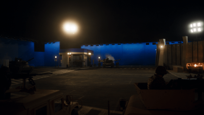 A darkly lit street set with a blue screen background.