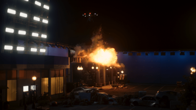 A large high rise building on fire on a dimly lit street, there is a blue screen at the end of the street.