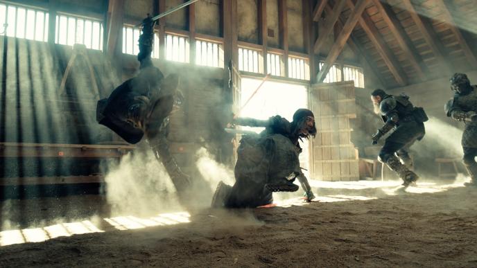 A group of people fighting with plastic stand ins for swords, they are jumping through the air and ducking close to the ground.