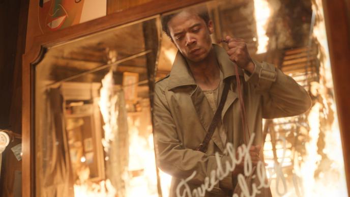 Interview with a Vampire Season 2: a young man sweeps up as he looks into a mirror with white swirling writing.