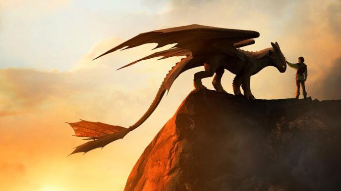 Hiccup and Toothless stand on a cliff edge against a sunset