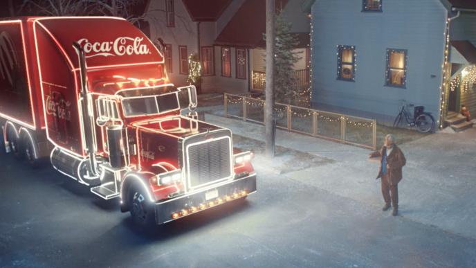 A bright red Coca Cola truck with VFX neon lights next to a man with pizza.