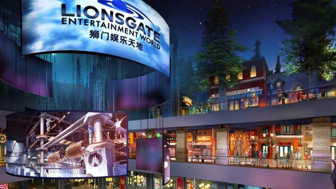 An outdoor retail location with a large electronic billboard showing Lionsgate in black text. There are multiple stories of shops and restaurants with people in.