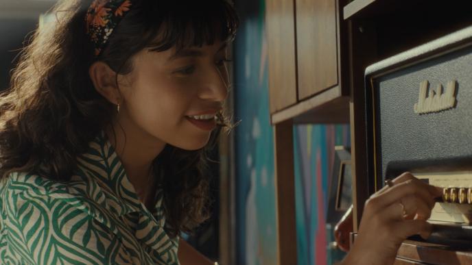 A woman adjusts a nob on an old radio