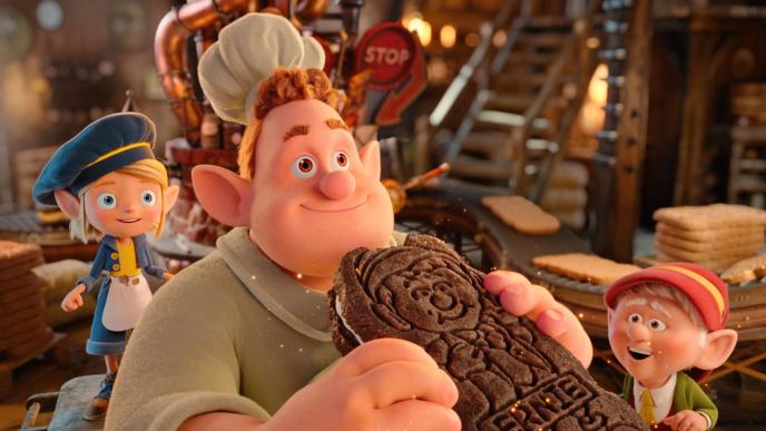 Three CG animated Keebler elves in the cookie factory. One eats a chocolate cookie