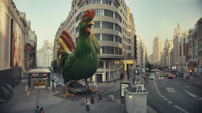 A large green CGI rooster walks through a city