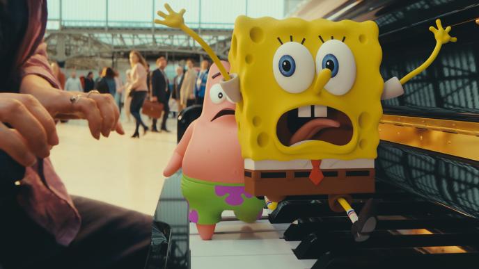 CG animated Spongebob Squarepants and Patrick Star run across a piano frantically in a train station