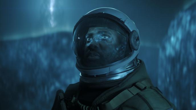 A person in a spacesuit stands in front of a neon blue extraterrestrial-like gaseous wall with an alien entity's silhouette looming