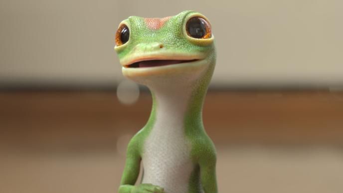 A close up of the CG animated GEICO Gecko who is standing with a grin on his face