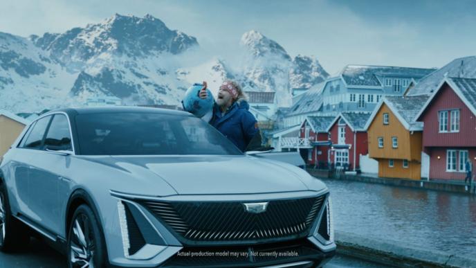 actor will ferrell standing outside of a car holding up a mobile phone while screaming. Norway in the background