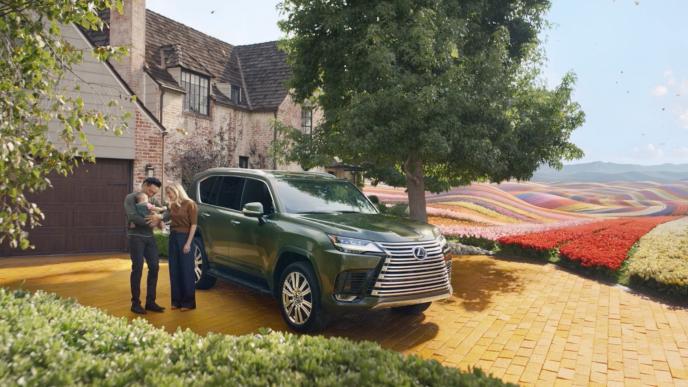 A family stands by a green Lexus SUV; Wicked director Jon M. Chu, his wife, and child, near Wicked's iconic flower field.