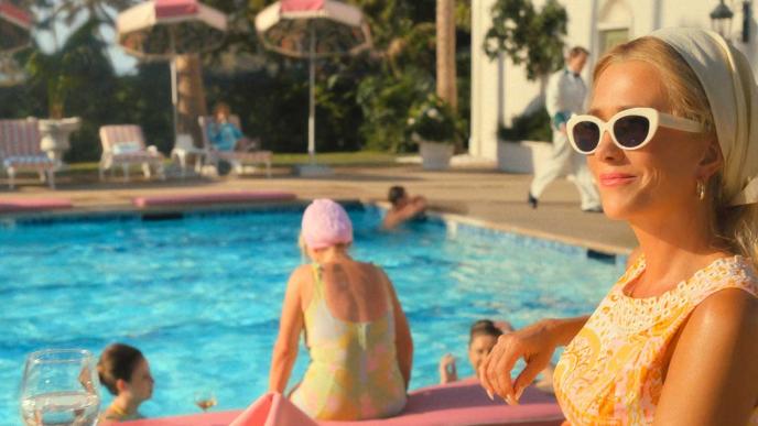 Kristen Wiig sits poolside in a 1960s holiday resort setting
