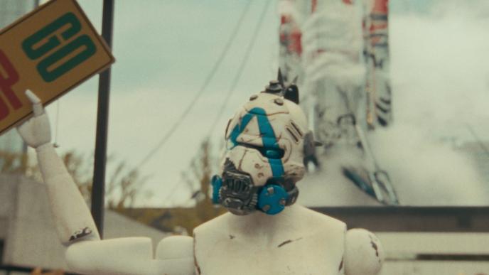 A white robot with a blue mask holds a sign that says "STOP GO"
