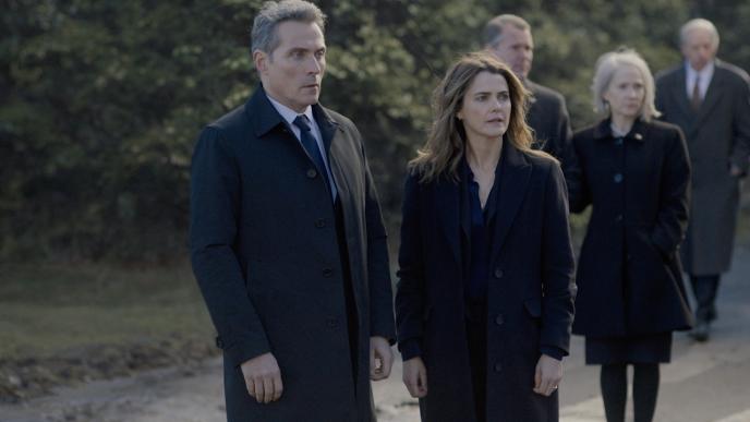 Kate Wyler (Keri Russell) and Hal Wyler (Rufus Sewell) in The Diplomat season 3. The two are in dark coats stand outdoors, appearing concerned as they look toward something unseen ahead together.