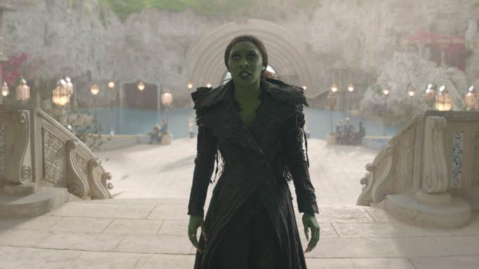 Cynthia Erivo as Elphaba in Wicked: For Good, walking up the steps of Shiz. The blue screen background has been replaced with a CGI Shiz University.
