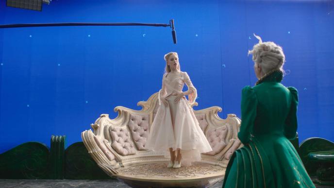 Ariana Grande as Glinda and Michelle Yeoh as Madame Morrible in Wicked: For Good. Glinda stands on her bubble platform in front of a blue screen backdrop
