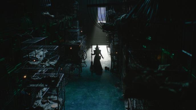 Elphaba finds the Wizard's secret animal prison in Wicked: For Good. Cynthia Erivo as Elphaba on set, in a dark vault full of empty cages