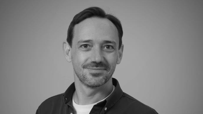 A black and white headshot of Dan Bethell