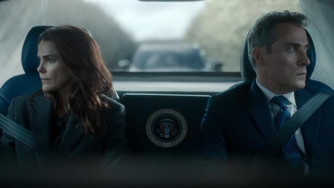 Keri Russell as Kate Wyler and Rufus Sewell as Hal Wyler in Netflix's The Diplomat Season 4 sit belted in the back of a government vehicle, gazing out opposite windows.