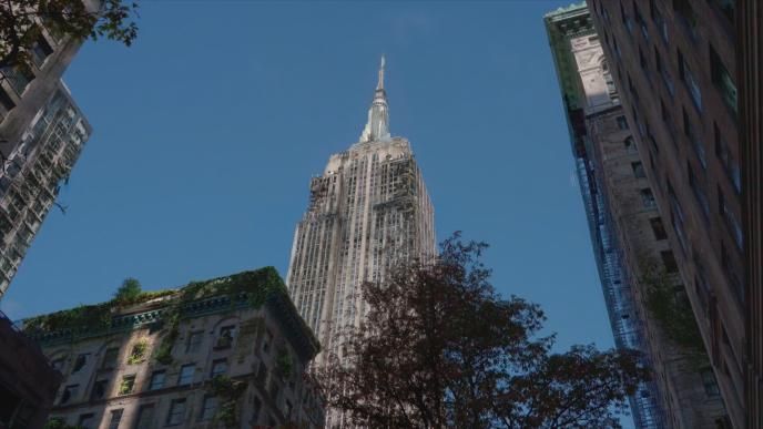 Low-angle view of the Empire State Building, weathered and overgrown with vegetation, framed by decaying buildings and trees.