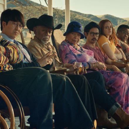 side view of a dog and nine people sitting in chairs outside of a porch