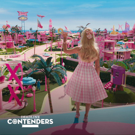 A still from the film Barbie showing Margot Robbie facing out over Barbie Land with the Deadline Contenders logo in the bottom left corner.