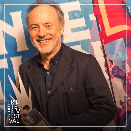 A photograph of Tim Webber at the Trieste Film Festival holding an award.