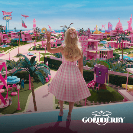 An image of Barbie facing out from the Barbie dream house over Barbie land waving, there is the Gold Derby logo in white in the bottom right corner.