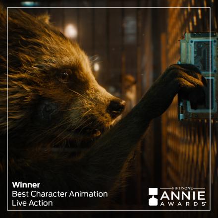 A raccoon is using a device to open the door to the cage he is in, there is the Annie Awards logo in the bottom right.