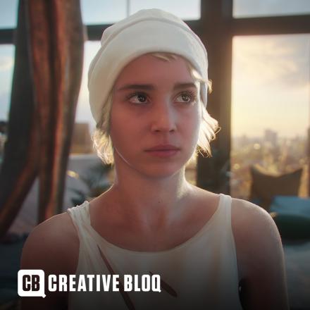 A woman in a white beanie hat and a white vest stands in front of a large wall of windows. 