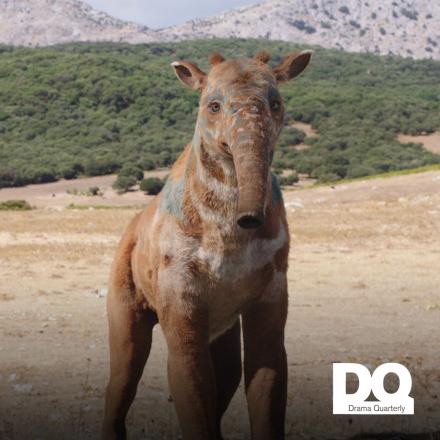 A photoreal elephant-like creature in a grassy landscape with the DQ logo in the bottom right corner.