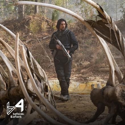 A man holding a gun is stood in amongst a large set of dinosaur bones.