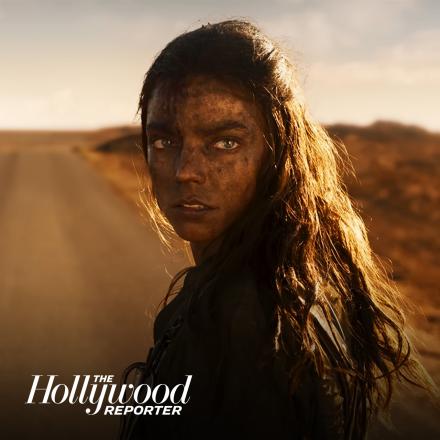 A woman with long brown hair and makeup on her forehead stood on a road in the middle of a desert.