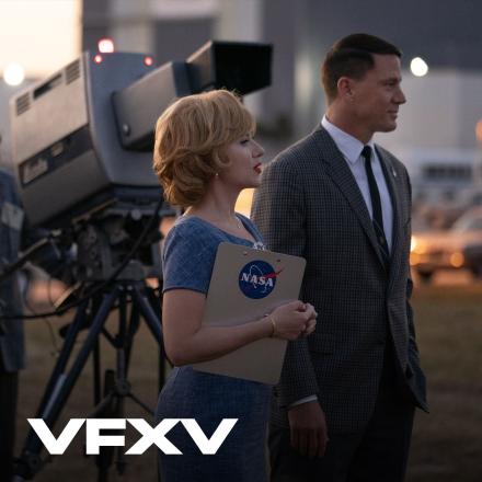 A man and and woman stood outside in front of a large 60's camera holding a NASA clipboard.