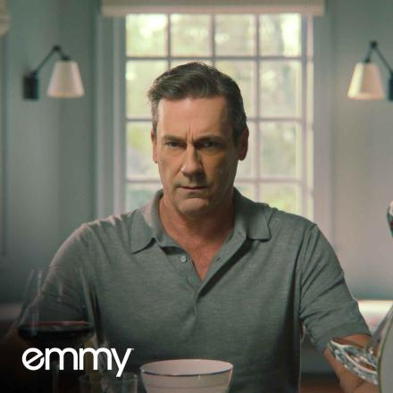 Jon Hamm in Your Friends & Neighbors opening title sequence. He is surrounded by glasses of red wine suspended in air. The Emmy Magazine logo sits in the bottom left corner