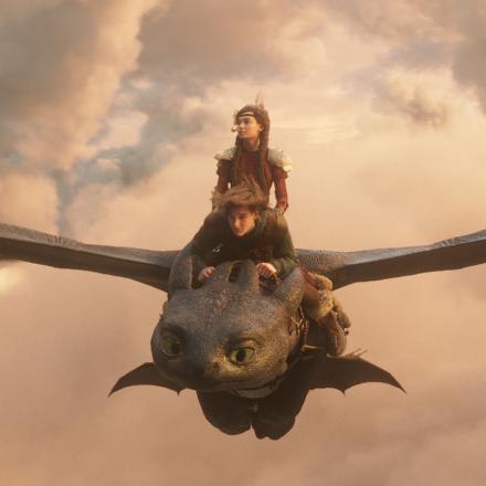 Realistic 3D animated dragon flying through sunset clouds with two riders in a cinematic scene from the live-action How to Train Your Dragon, showcasing advanced dragon animation and character VFX.