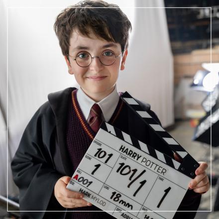 A photograph of a young Harry Potter actor holding a clapper board showing commencement of production.