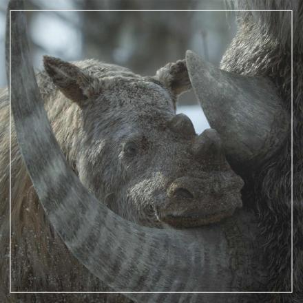 A prehistoric rhino-like figure with short fluffy skin rests in the tusks of a larger creature. The animals have been created in CGI for Apple TV+ new season of Prehistoric Planet