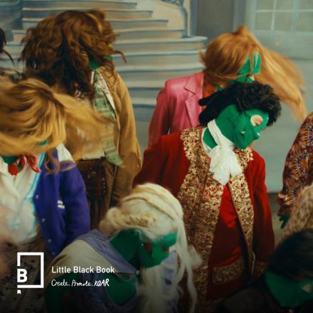 A behind the scenes still showing actors in TV show costumes and green screen suits. 