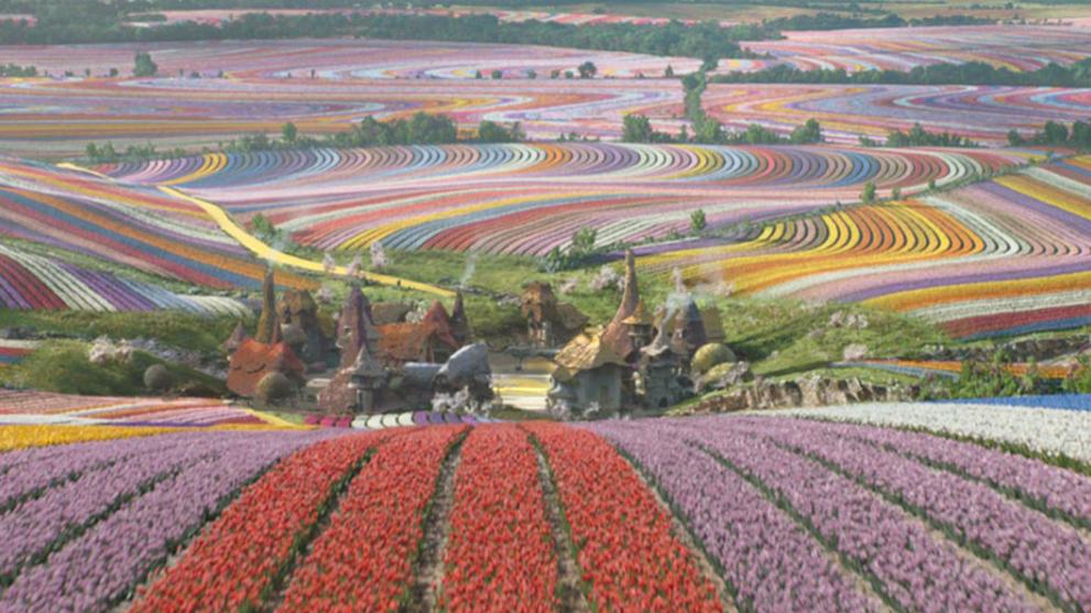 Wicked movie still: expansive landscape of bright, striped flower fields created with procedural VFX by Framestore. Highlights environment design and simulation.