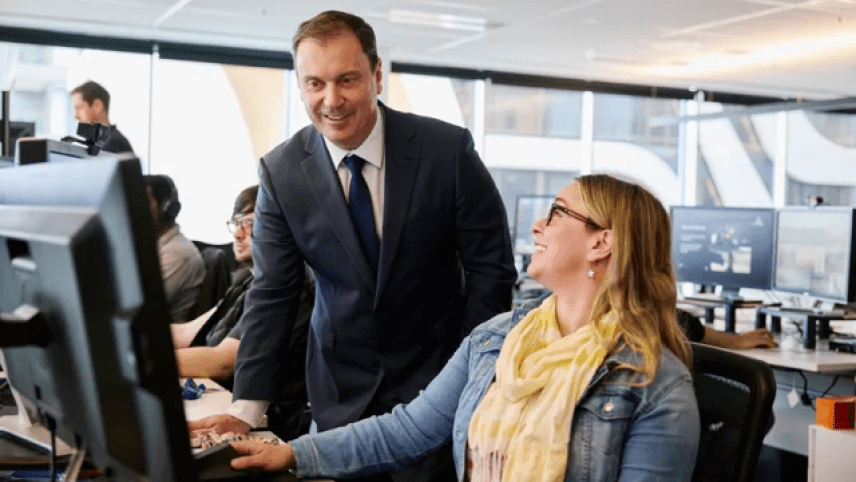 The Australian Creative Industries Minister looking over the shoulder of a junior animator looking at her work. 